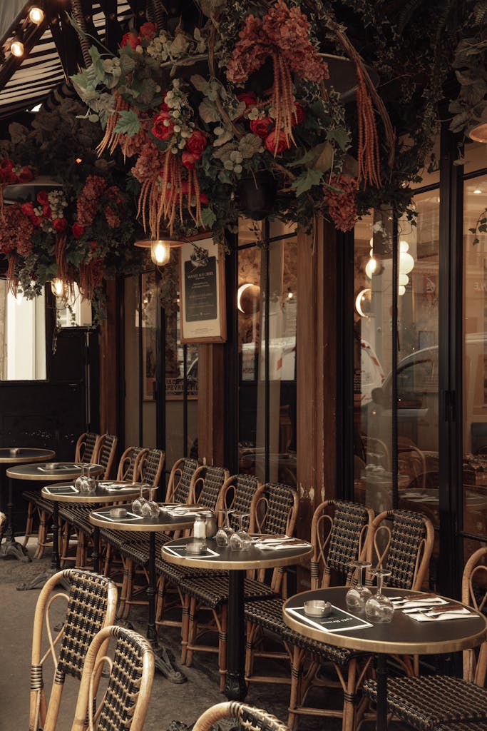 Experience the cozy atmosphere of a Parisian cafe terrace adorned with vibrant floral decor, ideal for outdoor dining.