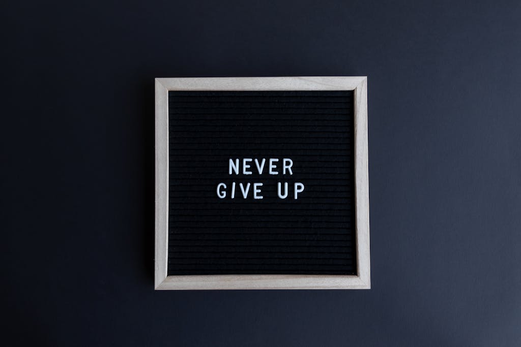 Inspirational letter board with 'Never Give Up' phrase on gray background.