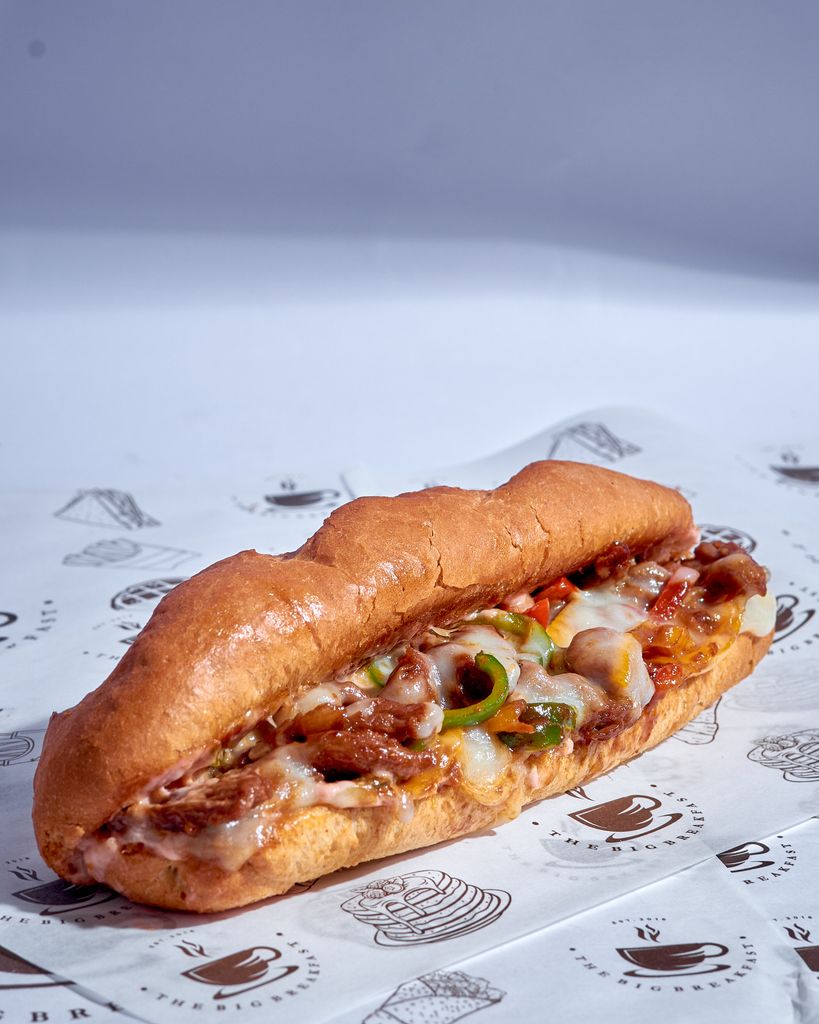 Close-up of a Philly cheesesteak sandwich with melted cheese and grilled vegetables, perfect for food lovers.