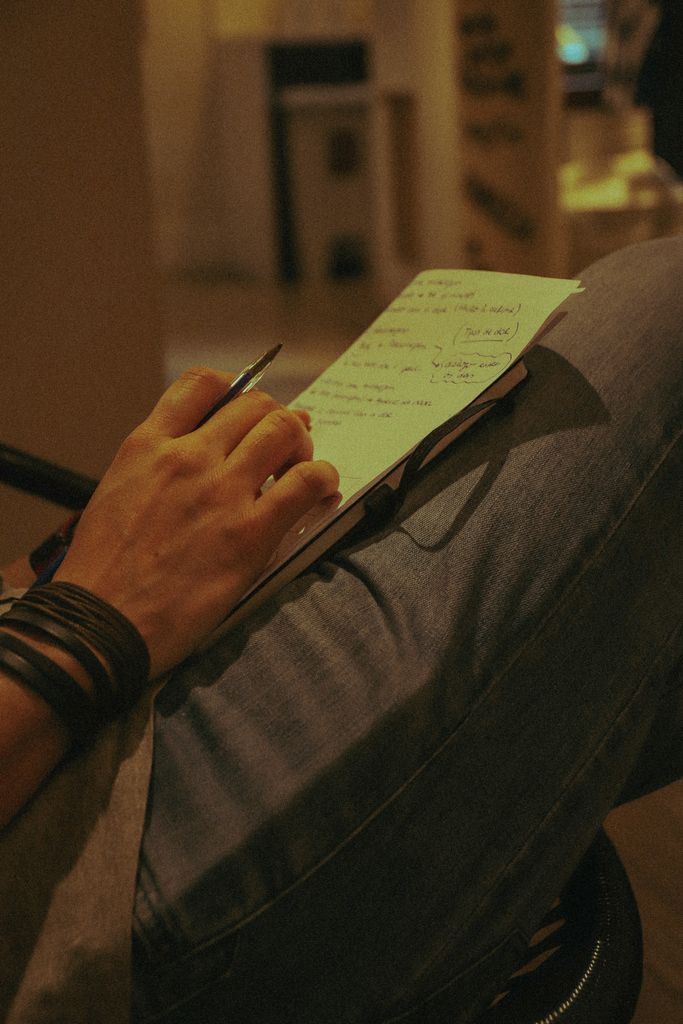 A person writing notes with a pen on paper indoors, focusing on creative thoughts.