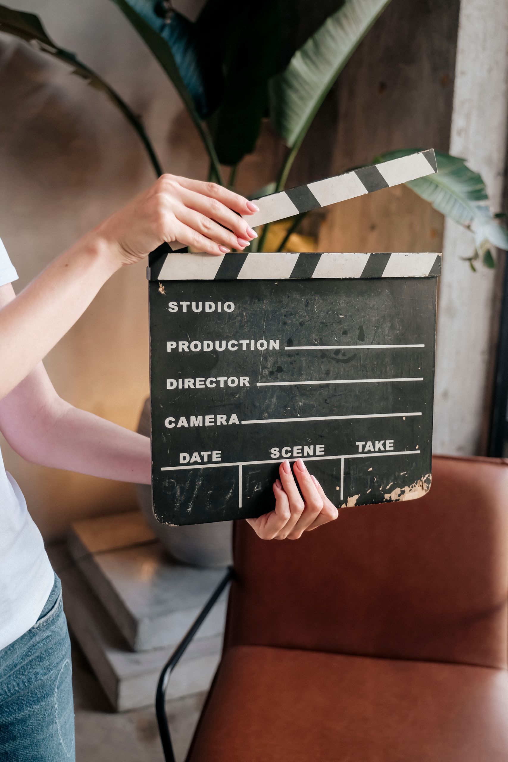 Close-up of hands holding a film slate board in an artistic indoor setting.